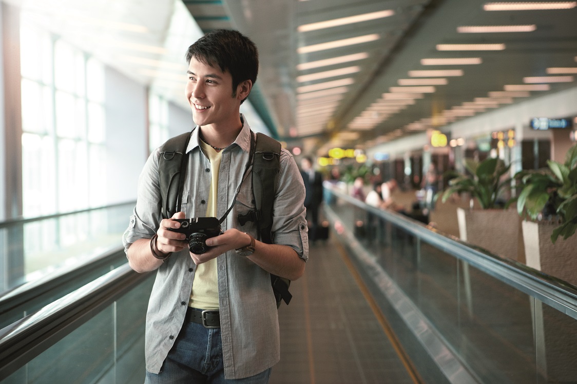 Traveller holding a camera on a travelator at Changi Airport. 